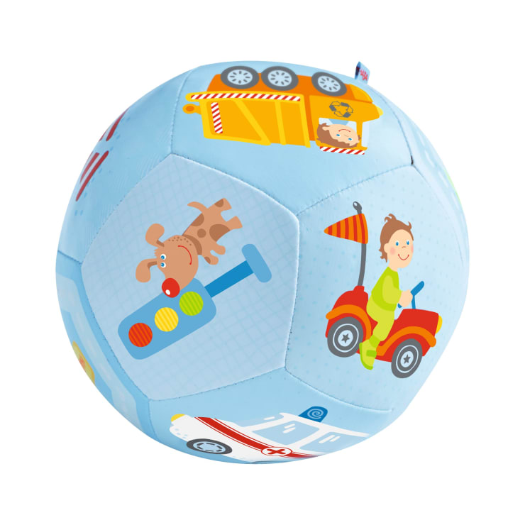 Ein hellblauer, weicher Ball, der mit farbenfrohen Illustrationen eines Kipplasters, eines Hundes auf einem Motorroller, eines lächelnden Kindes, das ein rotes Spielzeugauto fährt, und anderen verspielten Fahrzeugmotiven verziert ist.