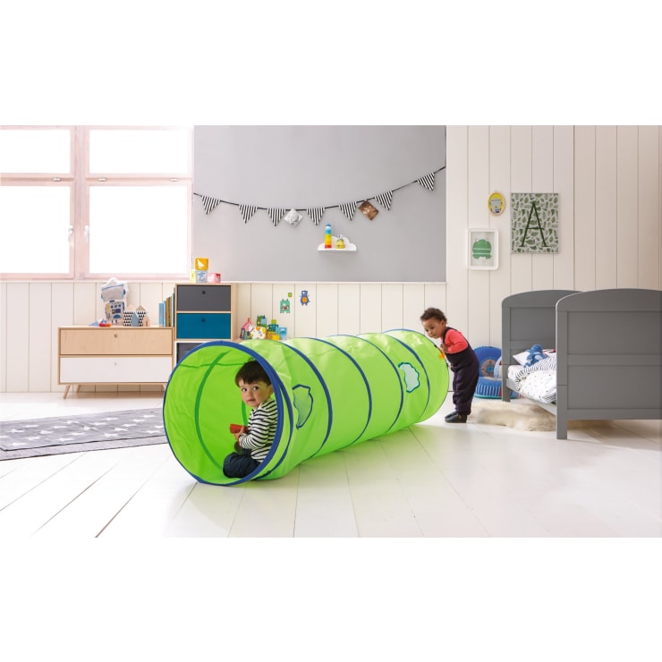 Zwei kleine Kinder spielen in einem Schlafzimmer. Ein Kind sitzt in einem grünen Spieltunnel und hält eine rote Tasse, während das andere Kind am Eingang des Tunnels steht. Das Zimmer ist mit Spielzeug, einem Bett und dekorativen Gegenständen an den Wänden ausgestattet.