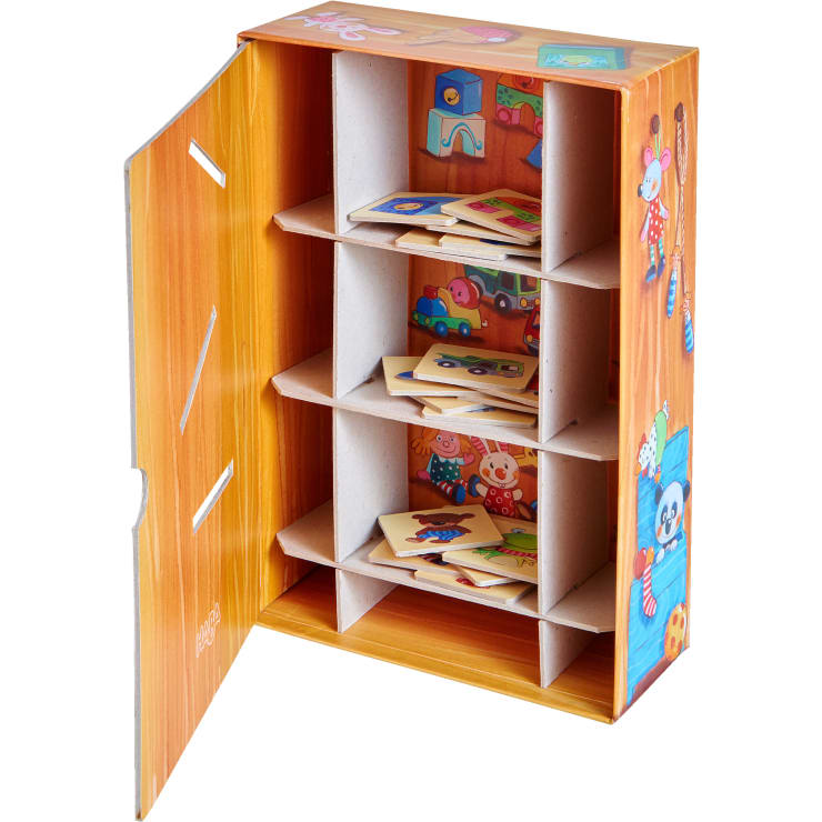 Eine Aufbewahrungsbox aus Karton mit vier Fächern, die jeweils illustrierte quadratische Fliesen enthalten. Die Schachtel ist mit Cartoon-Tieren und Spielzeugen verziert, und ihre Tür ist offen, um den Inhalt zu zeigen.