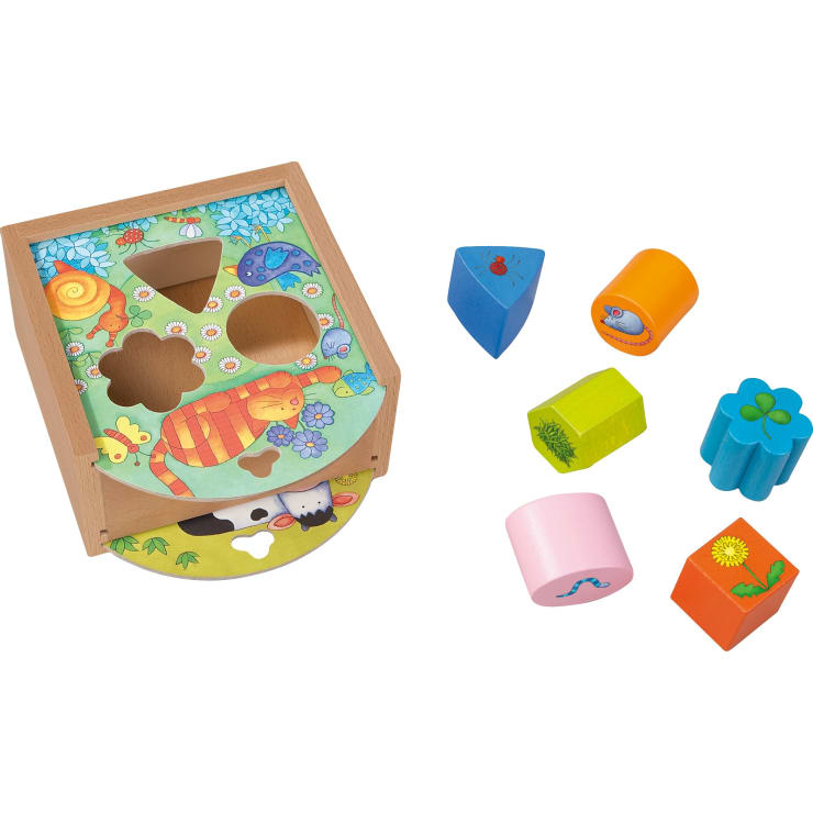 Ein Holzspielzeug zum Sortieren von Formen mit farbenfrohen Tier- und Naturillustrationen und sechs entsprechenden geometrischen Blöcken daneben: blaues Dreieck, orangefarbener Zylinder, grünes rechteckiges Prisma, blaues Kleeblatt, rosa Zylinder und rotes Dreieck.