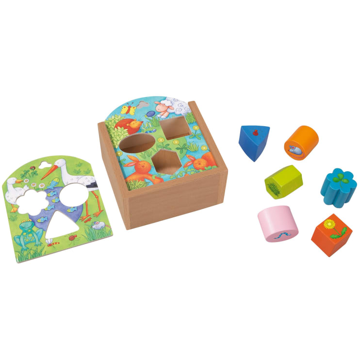 Ein Holzspielzeug zum Sortieren von Formen mit zwei illustrierten Deckeln, die jeweils verschiedene ausgeschnittene Formen zeigen, und acht bunten geometrischen Teilen mit verschiedenen Bildern, die neben der Schachtel platziert sind.