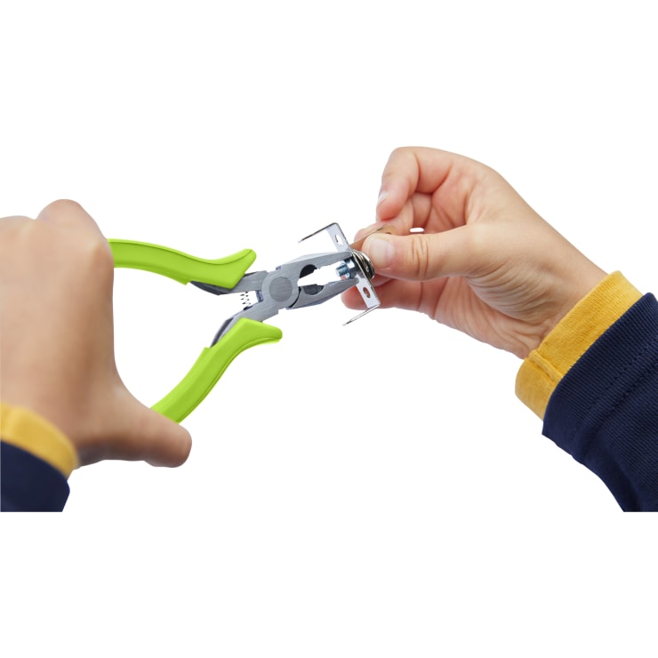Eine Person verwendet eine Zange mit grünem Griff, um einen kleinen Metallgegenstand zu greifen und zu biegen, während sie ihn mit der anderen Hand festhält.