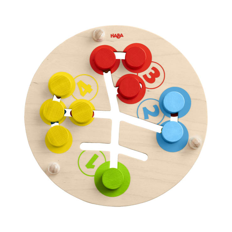 Ein rundes Holzpuzzle mit verschiebbaren Teilen in Rot, Gelb, Grün und Blau. Die Teile bewegen sich auf weißen Schienen und sind in der Nähe von nummerierten Abschnitten von 1 bis 4 gruppiert, passend zu ihren Farben. Oben steht die Marke HABA.