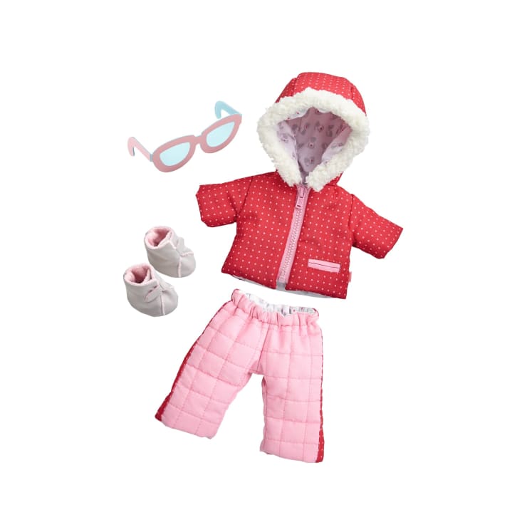 Eine Reihe von Puppenkleidern, darunter eine rote Kapuzenjacke mit weißem Saum, eine rosa Stepphose, weiße Schühchen und eine blau-rosa Katzenaugenbrille, alles auf weißem Hintergrund.