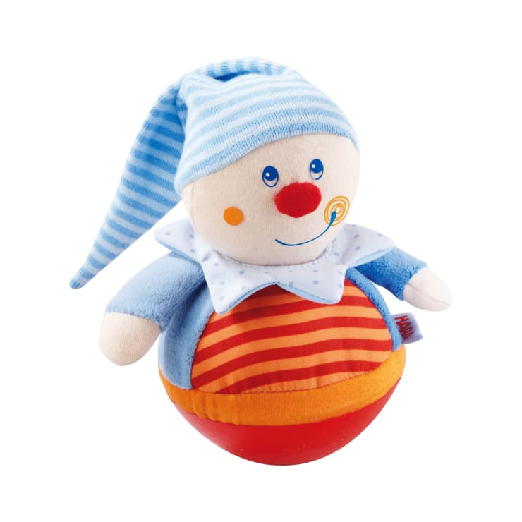 Eine weiche Clownspuppe mit rundem Po, blau-weiß gestreiftem Hut, blauem Outfit, weißem Kragen mit blauen Punkten und orange-rot gestreiftem Körper. Die Puppe hat eine rote Nase, orangefarbene Wangen und ein lächelndes Gesicht.