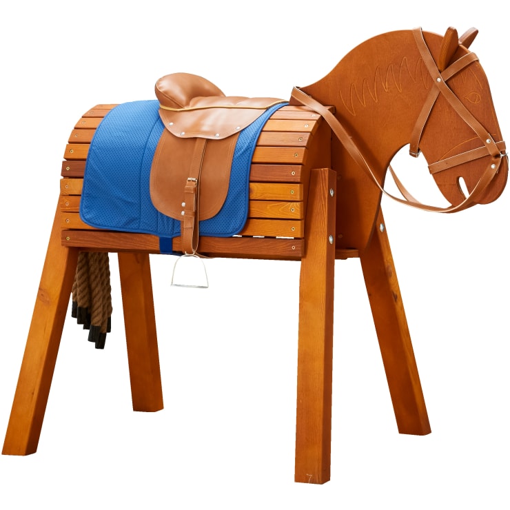 Ein Holzpferd mit braunem Ledersattel, blauer Schabracke, Steigbügeln und Seilschweif steht auf vier kräftigen Beinen. Der Pferdekopf ist mit einfachen Gesichtszügen und einem Zaumzeug geschnitzt.