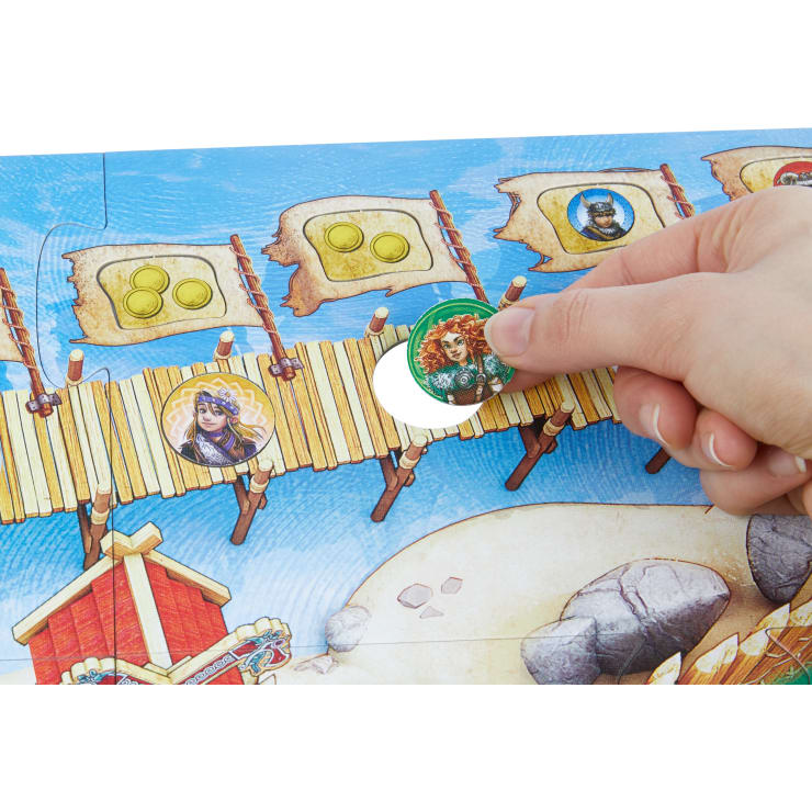 Eine Hand bewegt einen runden Spielstein mit einer rothaarigen Figur auf ein hölzernes Brückenfeld eines bunten Brettspiels. Auf dem Spielbrett sind weitere Spielfiguren und Münzfelder zu sehen.