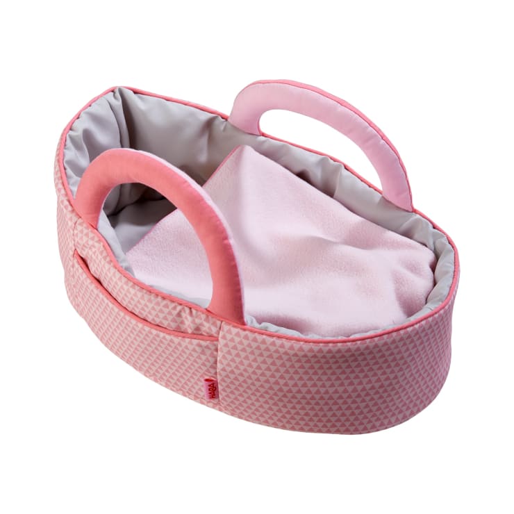 Eine kleine Puppentasche aus rosa und grauem Stoff mit zwei gepolsterten Griffen und einer weichen rosa Decke im Inneren, die auf einem weißen Hintergrund abgebildet ist.