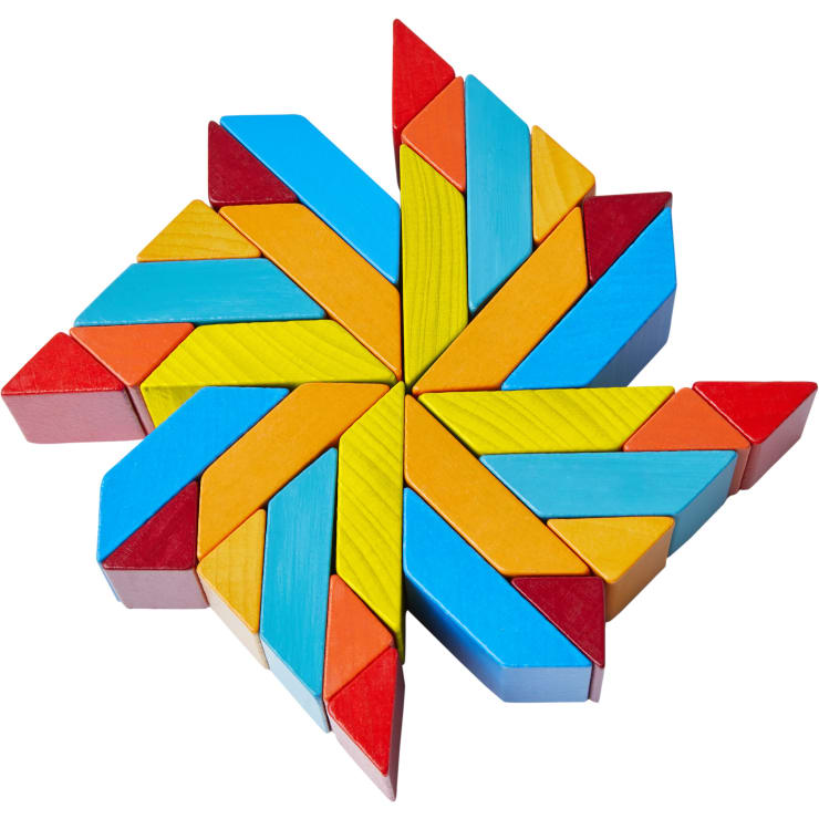 Geometrische Anordnung von bunten Holzklötzen, darunter Dreiecke und Parallelogramme, die ein symmetrisches Sternmuster mit roten, gelben, blauen und orangen Teilen bilden.
