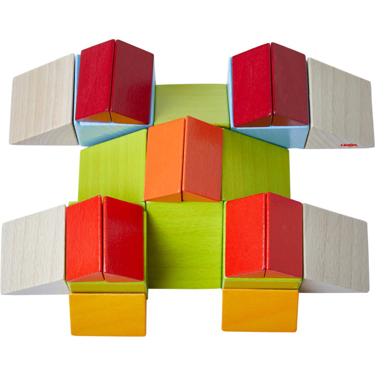 Eine symmetrische Anordnung von bunten Holzklötzen, darunter rote, orange, grüne und helle Holzfarben, die ein geometrisches Muster auf weißem Hintergrund bilden.