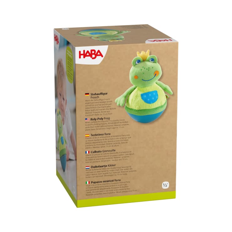 Das Produktinformationsblatt enthält vier Kinderspielzeuge mit Froschmotiven und Beschreibungen in Deutsch, Französisch, Englisch und Niederländisch. Rechts unten ist ein grüner, blauer und gelber Plüschfrosch mit einem lächelnden Gesicht abgebildet.