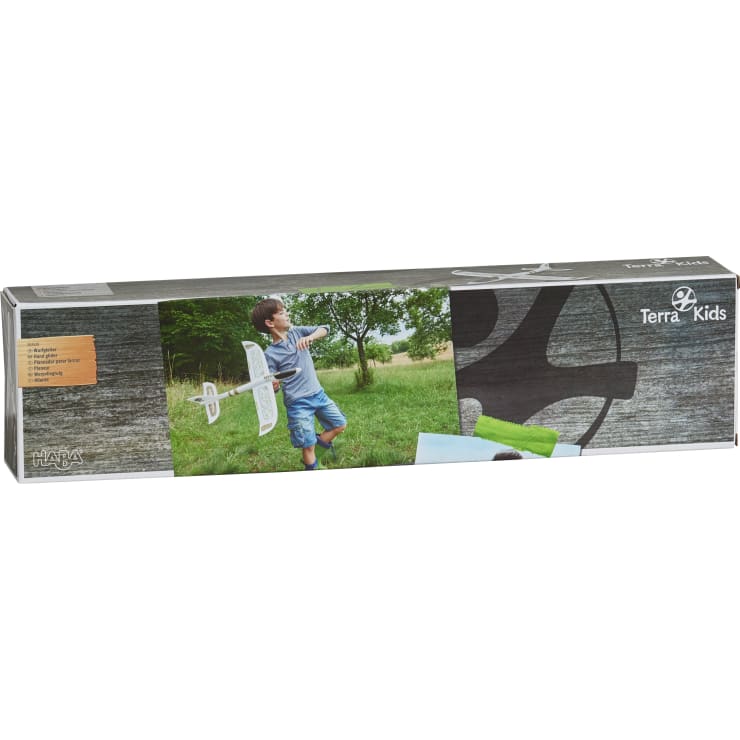 Eine rechteckige Schachtel für ein Terra Kids Produkt von HABA, die ein Kind in einem Park zeigt, das dabei ist, ein Schaumstoffgleitflugzeug zu werfen. Die Schachtel enthält das Produkt-Branding und Bilder des Segelflugzeugs im Einsatz.