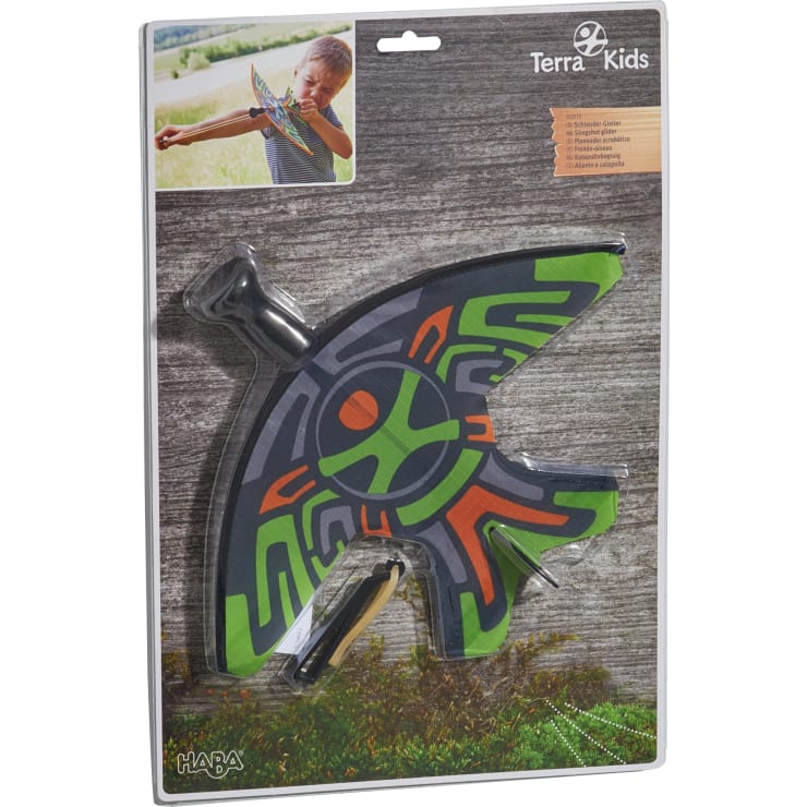 Ein verpacktes Terra Kids Bumerang-Set zeigt einen bunten Bumerang mit grünen, orangen und grauen Mustern. Die Verpackung enthält einen kleinen Griff, und in der oberen linken Ecke ist ein Foto eines Jungen abgebildet, der mit dem Bumerang spielt.