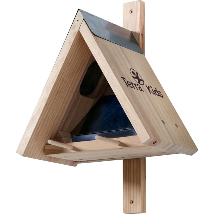 Ein hölzernes, dreieckiges Vogelhaus mit einem Metalldach, das auf einem vertikalen Holzpfosten montiert ist. An der Seite befindet sich ein rundes Einflugloch und auf der Vorderseite ist der Text Terra Kids mit einem Logo aufgedruckt.