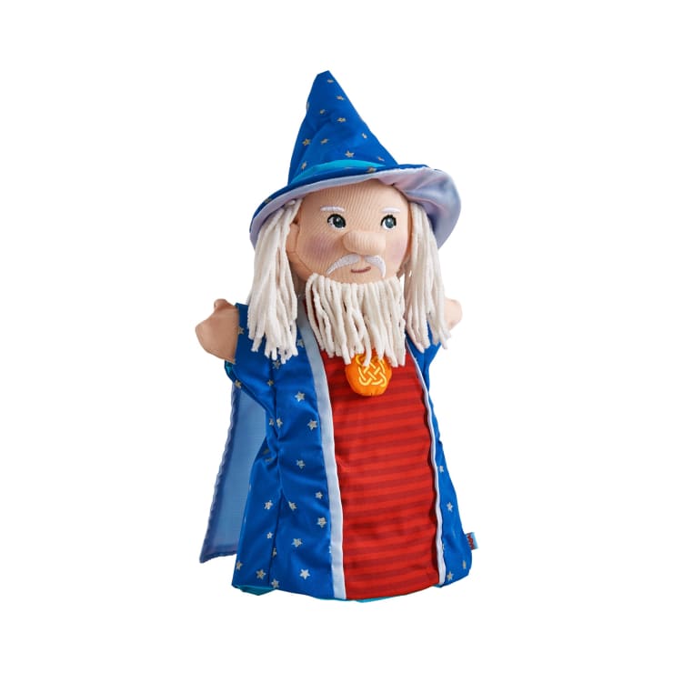 Eine Handpuppe aus Stoff in der Gestalt eines Zauberers, der einen blauen Hut und ein Gewand mit Sternmustern, ein rotes Hemd, weißes Haar und Bart aus Garn und ein orangefarbenes Medaillon vor weißem Hintergrund trägt.