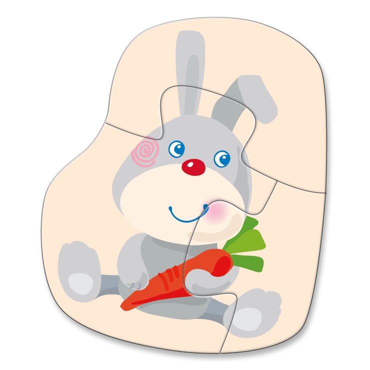 Ein vierteiliges Puzzle, das ein graues Kaninchen mit rosafarbenen Wangen zeigt, das eine orangefarbene Karotte hält, vor einem einfarbigen, hellen Hintergrund.