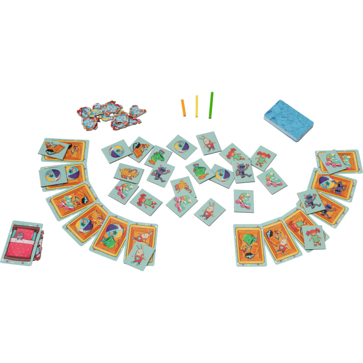 Ein Tischspiel mit illustrierten Karten, auf denen Tiere, Roboter und Menschen abgebildet sind, drei farbigen Stöcken, mehreren kleinen Spielsteinstapeln und einem Stapel blau gemusterter Karten, die alle auf einem weißen Hintergrund angeordnet sind.