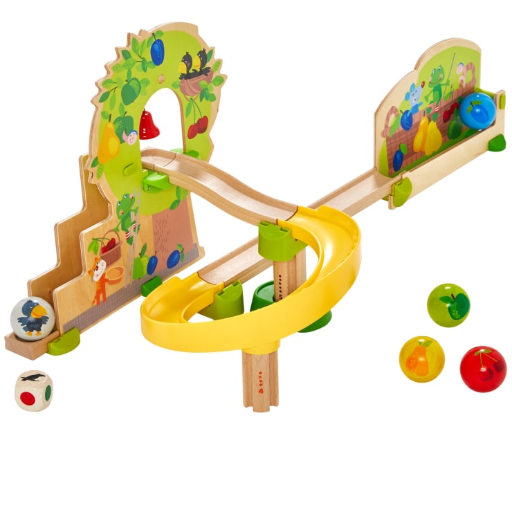 Eine hölzerne Kugelbahn mit bunten Obst- und Tierillustrationen, einer gelben Spiralrampe, verschiedenen Bahnen, einem Holzwürfel und vier Kugeln mit verschiedenen Obstmotiven.