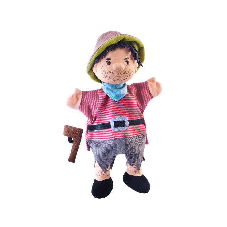 Eine Plüschpuppe als Pirat gekleidet, mit einem gestreiften roten Hemd, grauen zerrissenen Shorts, einem grünen Hut und einem blauen Halstuch. Die Puppe hat einen angemalten Bart und hält eine braune Spielzeugpistole.