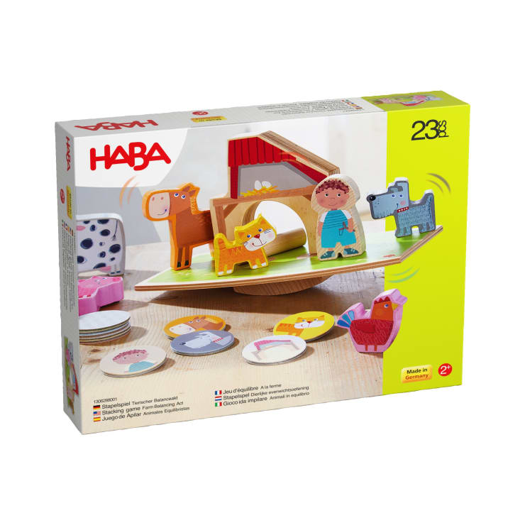 Eine Schachtel mit dem HABA-Tierbalancierspiel für Kinder ab 2 Jahren. Die Vorderseite zeigt Holztiere und -figuren, eine Scheune und eine Balancierplattform. Das Set enthält 23 Teile und ist in mehreren Sprachen beschriftet.
