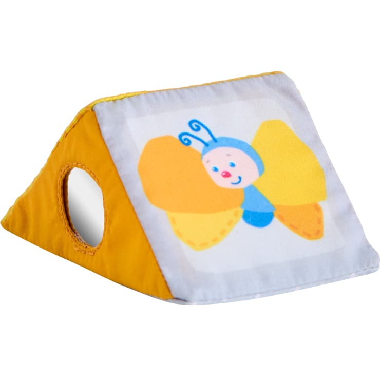 Ein kleines, dreieckiges, gelbes Stoffspielzeug mit einem kreisförmigen Loch auf einer Seite und der Abbildung eines lächelnden Schmetterlings mit orangefarbenen und gelben Flügeln auf einem weißen Aufnäher auf der Vorderseite.