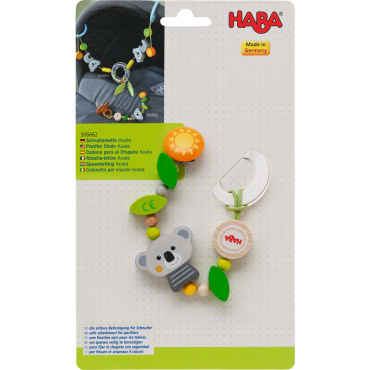 Eine HABA-Schnullerkette mit Koala-Motiv, Holzperlen, grünen Blättern und einem Clip auf einer gelb-weißen Produktverpackung mit mehrsprachigem Text und dem Label Made in Germany.