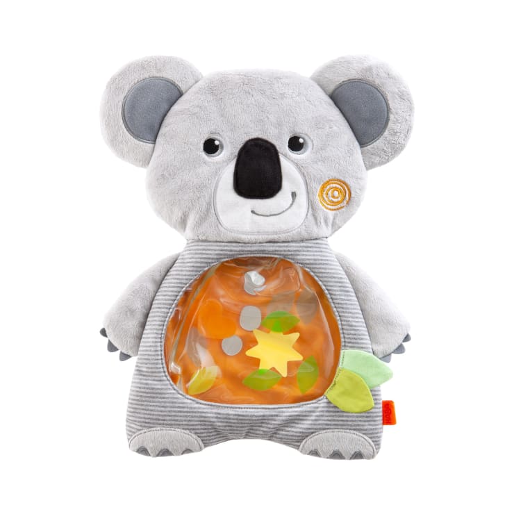 Ein Plüschtier in Form eines grauen Koalabären mit einer durchsichtigen Bauchtasche, die bunte Figuren enthält. Der Koala hat ein lächelndes Gesicht, runde Ohren und einen weichen, strukturierten Körper.