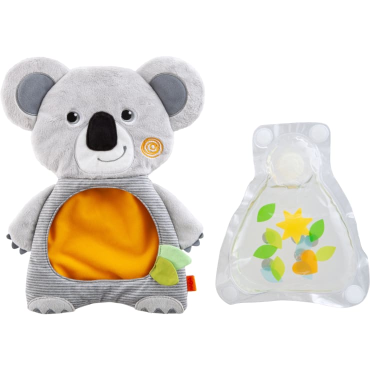 Ein grauer Plüsch-Koala mit gelb-orangem Bauch und einem kleinen grünen Blatt, daneben eine durchsichtige Gelpackung mit bunten Formen darin, beides vor weißem Hintergrund.