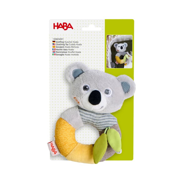 Ein Plüsch-Koala in Form eines Greifspielzeugs mit einem Ringmuster aus grauem, gelbem und orangefarbenem Stoff und zwei grünen Blattakzenten, abgebildet auf einer Verpackungskarte der Marke HABA. Ein beigefügtes Foto zeigt das Spielzeug an einem Kinderwagen befestigt.
