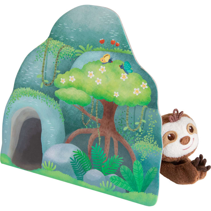 Ein Plüschfaultier lugt hinter einer Kartonillustration einer grünen Waldszene mit einem Baum, Felsen, Pflanzen, einer Höhle und zwei Schmetterlingen auf einem Busch hervor.