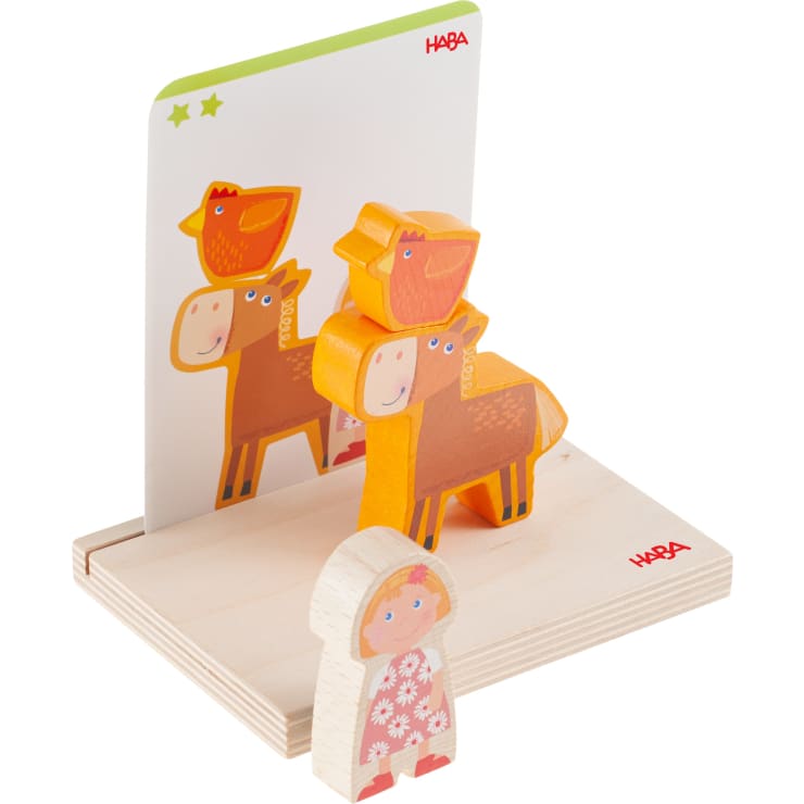 Ein Holzspielzeugset mit den Blockfiguren eines Pferdes, einer Kuh, zweier Vögel und eines Kindes auf einem Holzsockel mit einer vertikalen illustrierten Karte, die die gleiche Tieranordnung zeigt.