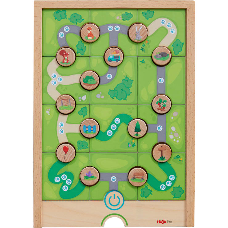 Ein hölzernes Puzzlespielbrett mit grünen Pfaden und zwölf runden Holzplättchen, die Bilder wie Tiere, ein Auto, einen Ballon, Bäume und eine Blume zeigen. Das Spielbrett hat ein blaues Machtsymbol in der unteren Mitte.