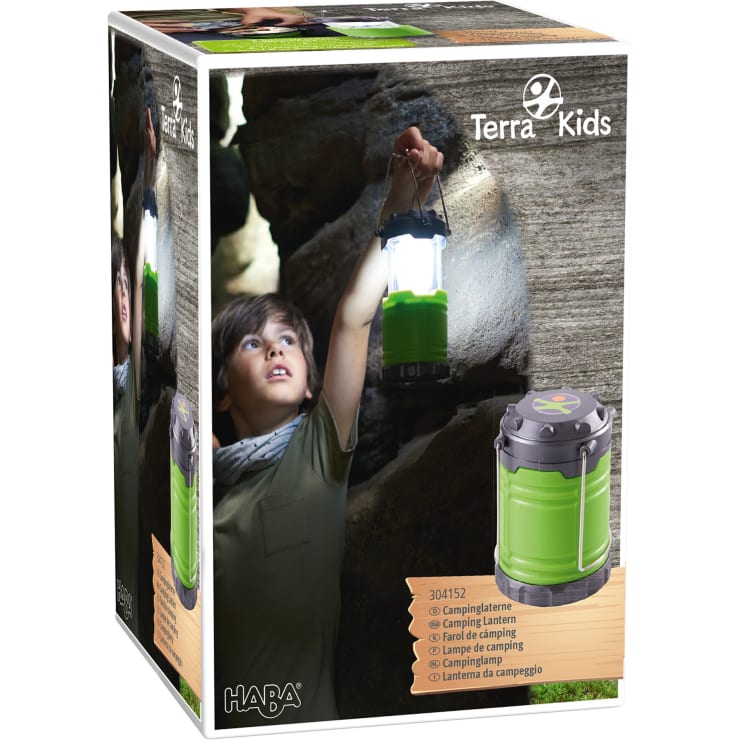 Eine Produktverpackung für eine HABA Terra Kids Campinglaterne. Die Schachtel zeigt ein Kind, das eine grüne Campinglaterne in einer felsigen Umgebung im Freien hält, mit einem Bild der Laterne und Produktinformationen auf der Vorderseite.