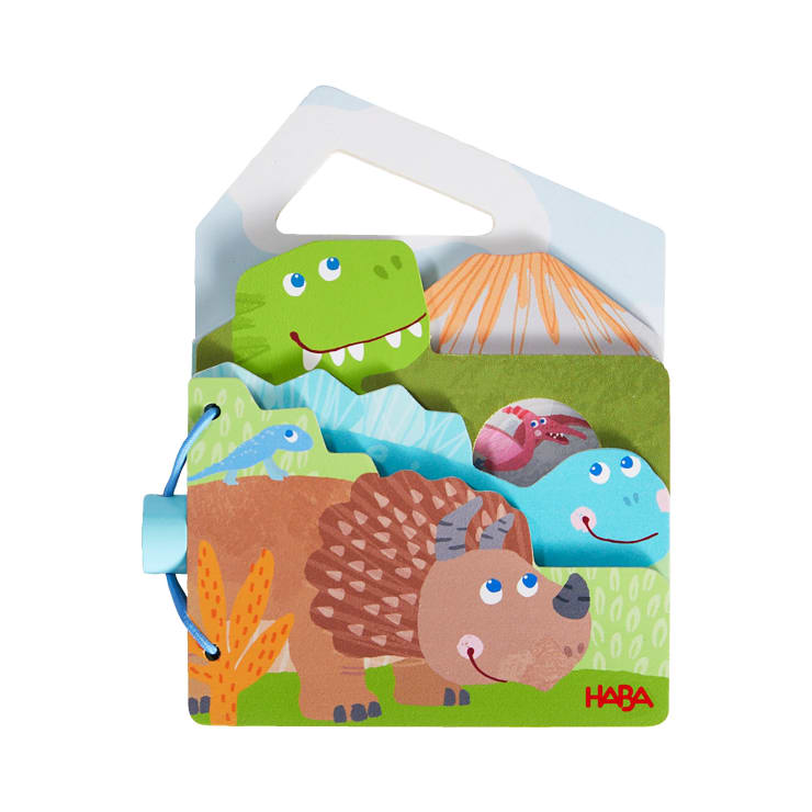 Ein farbenfrohes Kinderbuch mit Illustrationen von lächelnden Dinosauriern und prähistorischen Landschaften, gebunden mit einer blauen Kunststoffspirale und mit einem Griff am oberen Rand zum einfachen Tragen. Die Marke HABA ist in rot aufgedruckt.