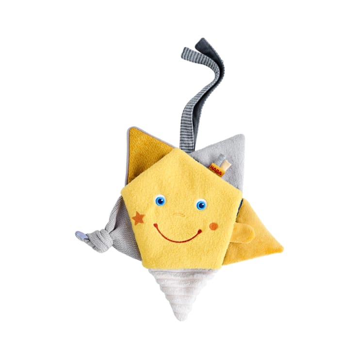 Ein weiches, plüschiges Babyspielzeug in Form eines lächelnden Sterns mit aufgenähten Augen, einem roten Lächeln und einem kleinen Sterndetail. Es hat gelben und grauen Stoff, einen gestreiften Kegelboden und ein Schlaufenband an der Oberseite.