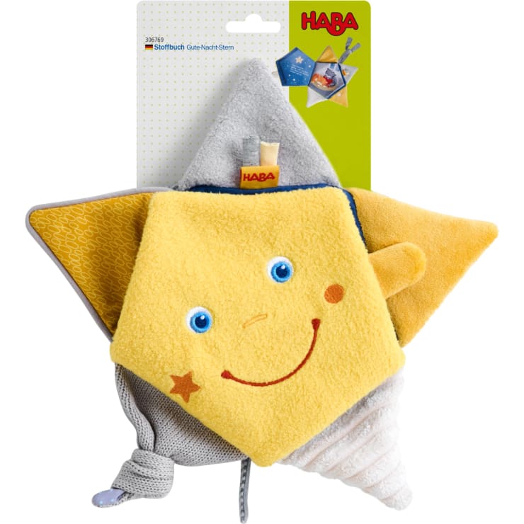 Ein plüschiges, gelbes, sternförmiges Babyspielzeug mit einem lächelnden Gesicht, roten Wangen und kleinen Stoffanhängern, die auf einer Pappunterlage mit dem HABA-Markenlogo und Produktinformationen angebracht sind.