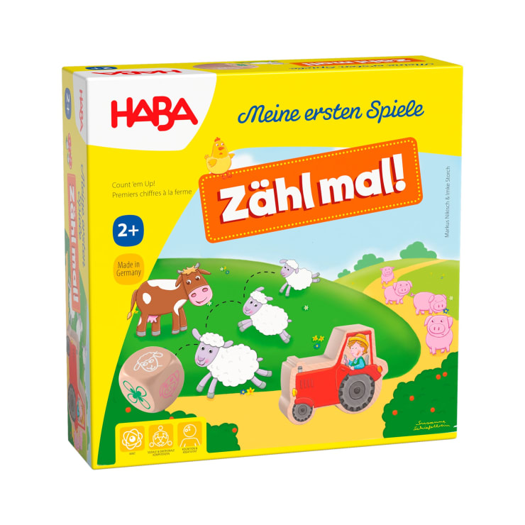 Eine gelbe Schachtel des HABA-Spiels Zähl mal! für Kinder ab 2 Jahren mit Cartoon-Bauernhoftieren, einem roten Traktor, einem Würfel und dem Text Meine ersten Spiele mit englischen, französischen und deutschen Beschreibungen.