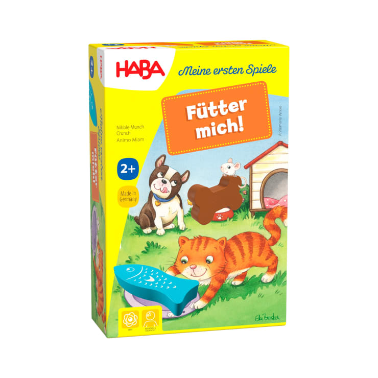 Eine farbenfrohe Schachtel des HABA-Spiels Füttert mich! für Kinder ab 2 Jahren mit Illustrationen einer Katze, eines Hundes und eines Kaninchens im Freien und einem großen blauen Fischspielzeug im Gras im Vordergrund.