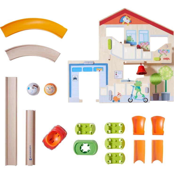 Ein Set mit Holz- und Plastikspielzeugteilen, darunter gebogene Gleise, gerade Gleise, ein rotes Spielzeugauto, zwei runde Figuren, grüne Verbindungsstücke, orangefarbene Rampen und ein Puppenhausabschnitt mit Abbildungen.
