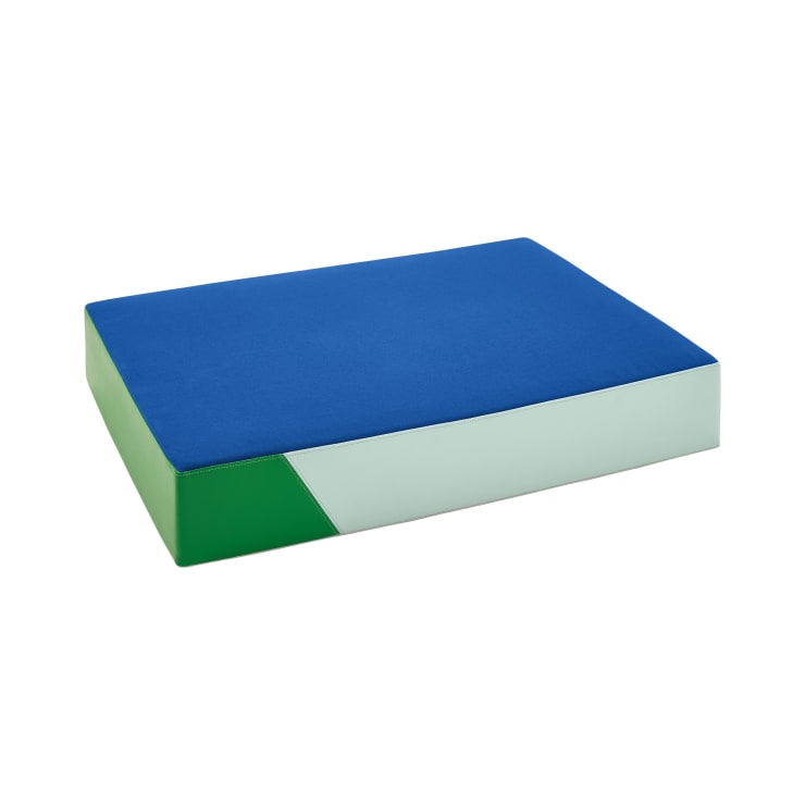 Eine rechteckige Schaumstoffmatte mit einer blauen Oberseite, grünen Seiten und einem weißen diagonalen Akzent auf weißem Hintergrund.