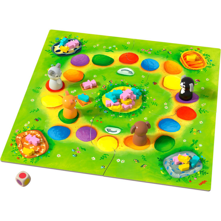 Ein farbenfrohes Brettspiel mit tierförmigen Spielsteinen, einem bunten Würfel und kleinen Holzplättchen in Form von Lebensmitteln oder Tieren. Das Spielbrett ist mit hellen Feldern, Körben und dekorativen Illustrationen von Gras und Blumen versehen.