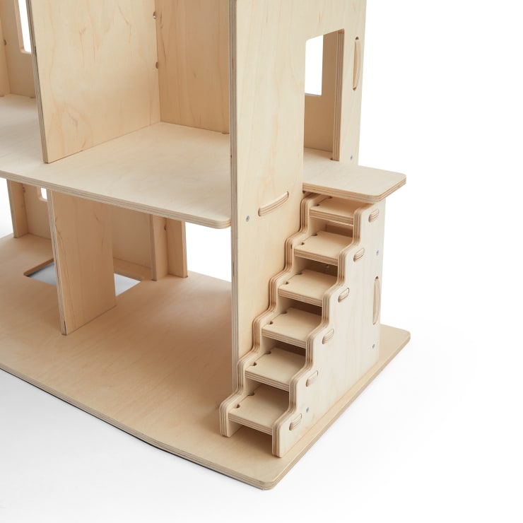 Ein hölzernes Puppenhaus mit einer Treppe mit fünf Stufen, die vom Erdgeschoss ins Obergeschoss führt, hergestellt aus hellem Sperrholz mit sichtbaren Fugen und Schlitzen.