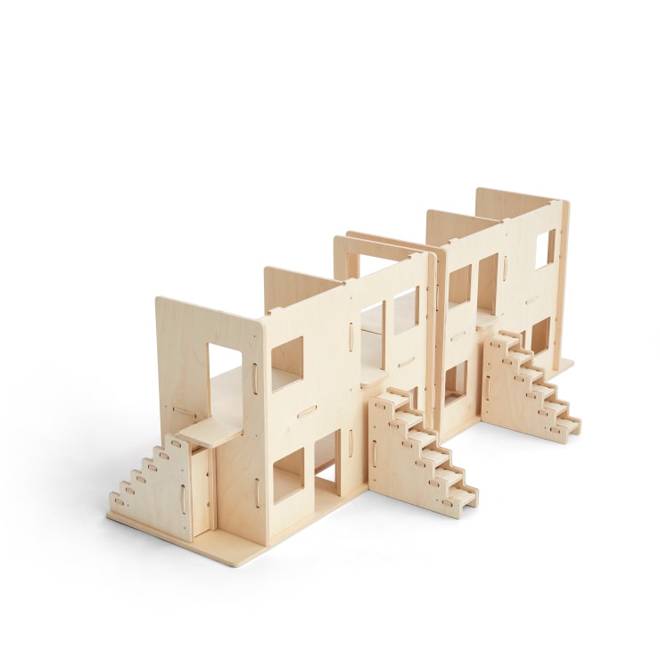 Eine modulare Puppenhausstruktur aus Holz mit mehreren Räumen, Treppen und offenen Fenstern. Das Design ist minimalistisch, und die Teile sind aus hellem Holz. Der Hintergrund ist einfarbig weiß.
