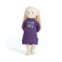 Eine Stoffpuppe mit heller Haut, blondem Garnhaar und einem lila Kleid, auf dem steht, dass jeder Tag ein sonniger Feiertag ist, steht aufrecht vor einem weißen Hintergrund.