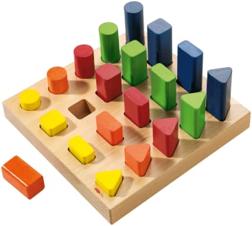 Ein Holzspielzeug zum Sortieren von Formen mit einer quadratischen Grundfläche enthält Stifte in den Farben Gelb, Rot, Grün und Blau, die jeweils verschiedene geometrische Formen aufweisen: Zylinder, Rechtecke, Dreiecke und Quadrate. Ein gelbes Rechteck befindet sich außerhalb des Sockels.
