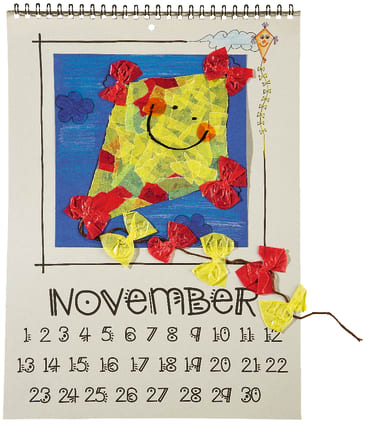 Ein handgemachtes Kalenderblatt für November zeigt ein lächelndes, abstraktes Gesicht aus zerrissenem Papier, mit roten und gelben Seidenpapierschleifen und einer kleinen Drachenzeichnung in der rechten oberen Ecke.