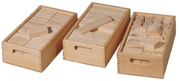 Drei Holzkisten mit keilgezinkten Ecken, die jeweils fein säuberlich geordnete geometrische Holzklötze in verschiedenen Formen enthalten, darunter Rechtecke, Zylinder und Bögen.