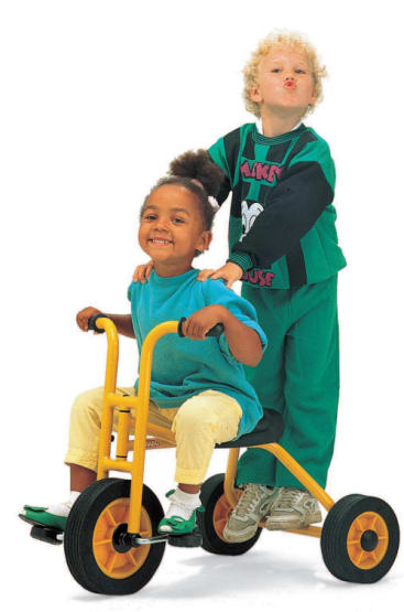 Zwei kleine Kinder posieren mit einem gelben Dreirad. Ein Kind hält lächelnd den Lenker, während das andere dahinter steht, die Hände auf die Schultern des sitzenden Kindes legt und ein verspieltes Gesicht macht.