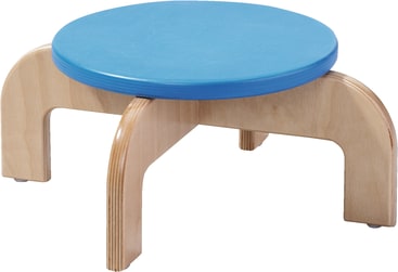 Ein kleiner Holzhocker mit vier gebogenen Beinen und einer runden blauen Sitzfläche. Der Hocker ist einfach im Design und scheint für Kinder oder niedrige Sitzgelegenheiten gemacht zu sein.