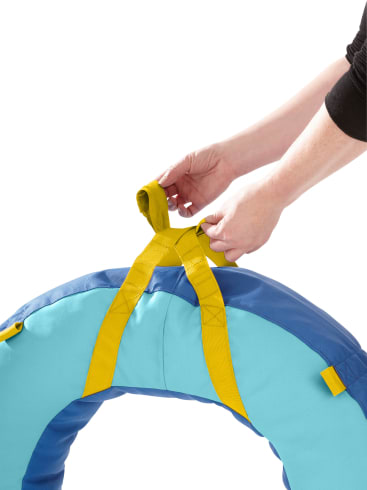 Die Hände einer Person umgreifen zwei gelbe Griffe, die an einem blauen und hellblauen gepolsterten Ring befestigt sind, vor einem weißen Hintergrund.